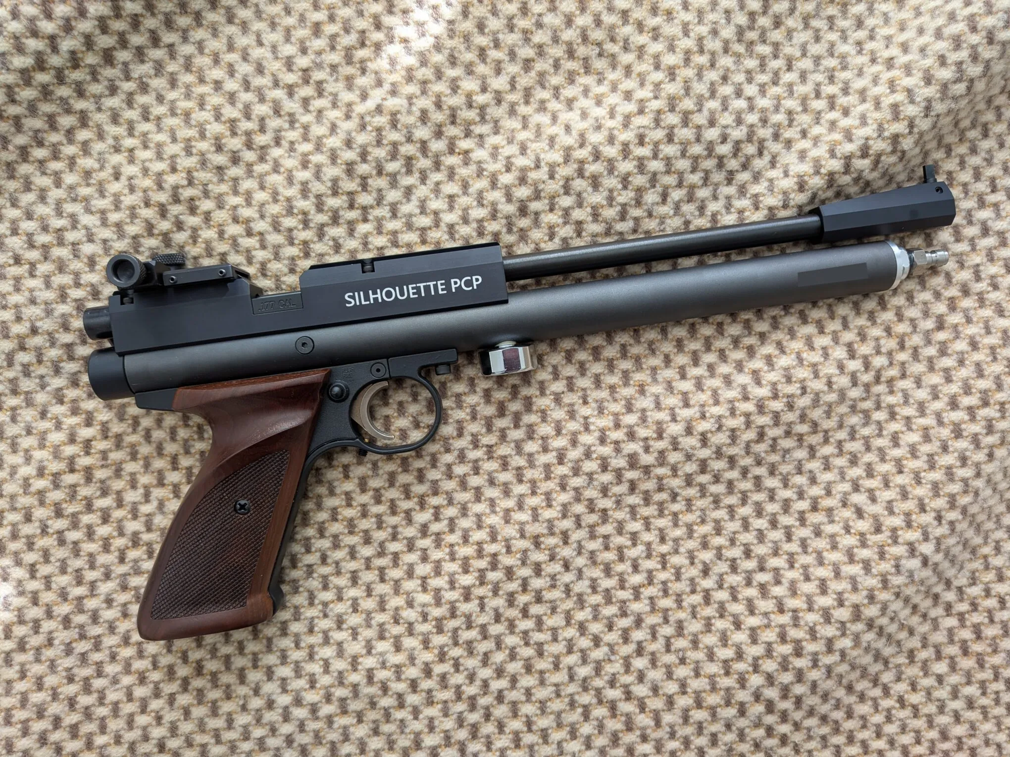 Side profile of the Crosman 1701P showing the exposed barrel, air reservoir, wooden grip, and Williams rear sight