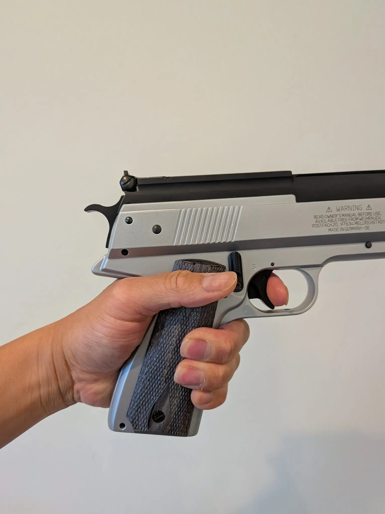 HW45 held in the left hand, showing the checkered grip panel and hand placement