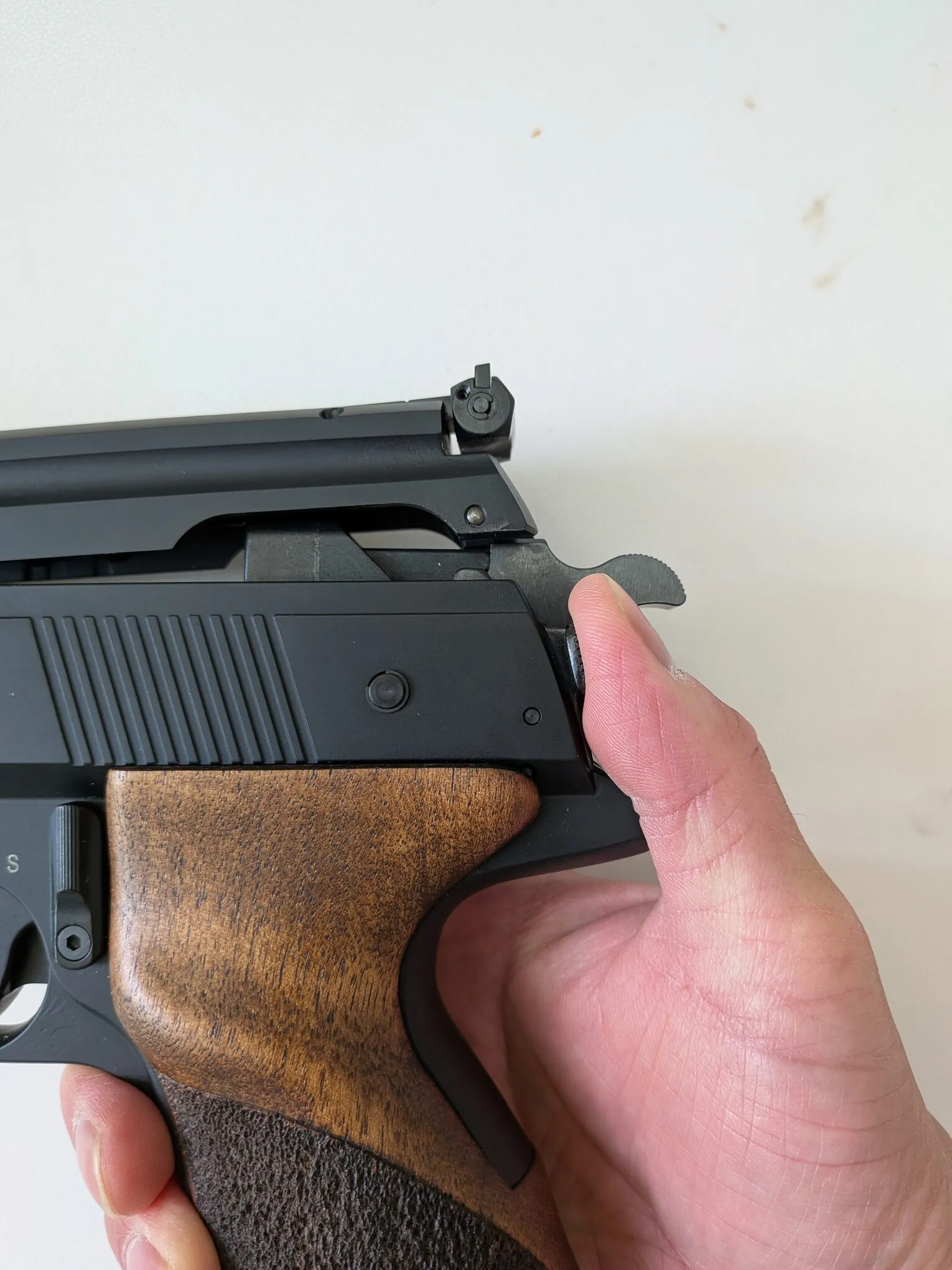 Thumb operating the release lever beside the HW75 hammer as the upper assembly opens
